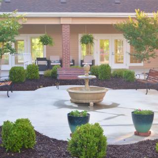 A serene courtyard with a central fountain, surrounded by lush greenery and seating areas.