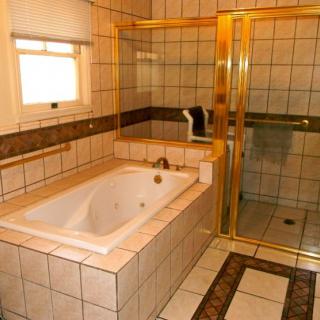 A tiled bathroom featuring a bathtub, shower enclosure, and window.