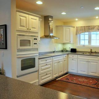 A modern kitchen with white cabinets and built-in appliances.