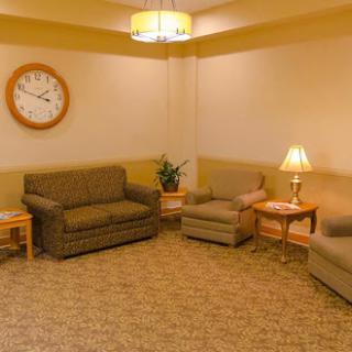 A cozy living room featuring comfortable sofas, a wall clock, a lamp, and a decorative plant.
