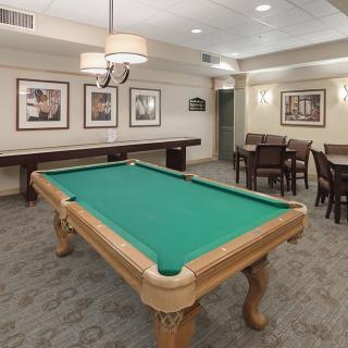 A cozy billiard room with a pool table, artwork, and seating area.