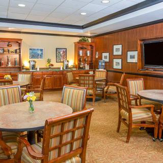 An elegant lounge with tables and chairs, featuring wood paneling and decorative elements.