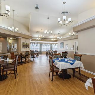 A spacious dining area with neatly arranged tables, chairs, and elegant chandeliers.