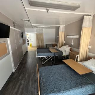 A view of a hospital patient room featuring two beds and modern amenities.