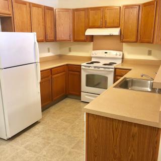 A kitchen featuring wooden cabinets, a white refrigerator, stove, and sink.