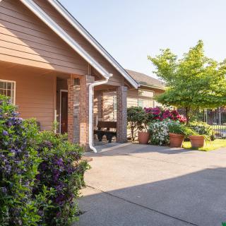 A sunny view of a house exterior with a driveway and well-maintained landscaping.