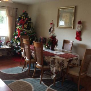 A cozy dining room decorated for Christmas with a festive tree and table setting.