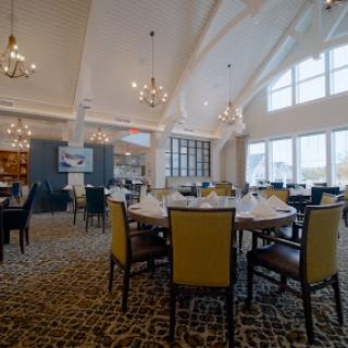 A beautifully designed restaurant interior featuring elegant tables and chairs, complemented by modern lighting and large windows.