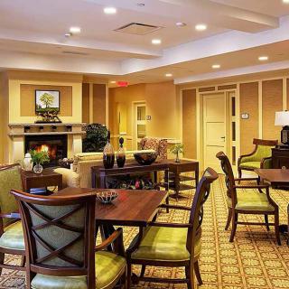 A cozy and well-furnished living area with multiple tables and chairs, featuring warm lighting and a fireplace.