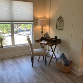 A cozy home office corner with a small wooden desk and chair beside a large window.