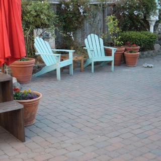 A cozy outdoor patio with Adirondack chairs and potted plants.