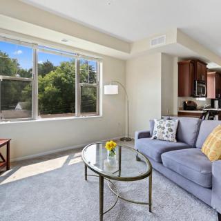 A bright and cozy living room with a sofa, coffee table, and large window offering a view of greenery.