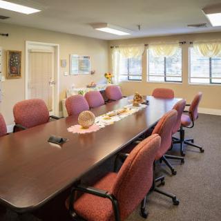 A spacious and well-lit conference room equipped with a long table and comfortable chairs, ideal for meetings and discussions.