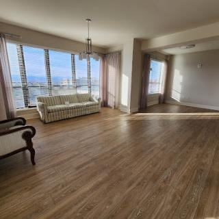 A spacious and bright living room featuring large windows, offering a panoramic view and an inviting atmosphere.