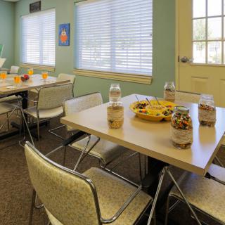 A community dining area with tables set up with snacks and chairs around them.