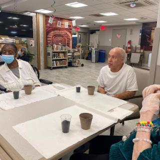 A group of senior citizens engaged in a discussion in a community healthcare setting.