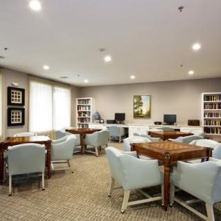 A quiet library with tables, comfortable chairs, and bookshelves filled with books.
