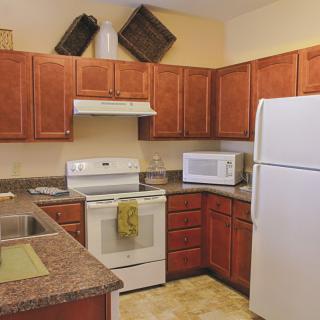 A cozy kitchen with wooden cabinets and modern appliances, including a refrigerator, oven, and microwave.