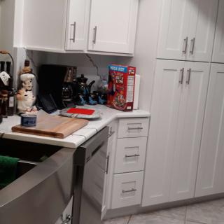 A modern kitchen with white cabinets and various items on the countertop.