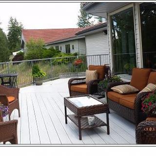 A cozy outdoor deck with seating and a table, surrounded by greenery.