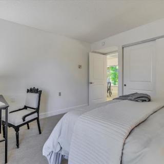 A bright and minimalist bedroom featuring a cozy bed and an elegant chair.