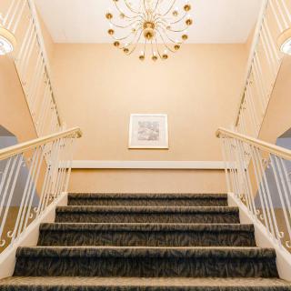 Elegant staircase with a chandelier and framed artwork.