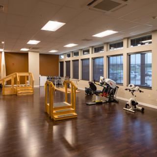 A spacious rehabilitation room equipped with exercise machines and therapy tools.