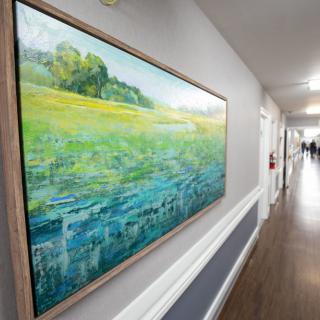 A hallway featuring a large landscape painting on the wall.