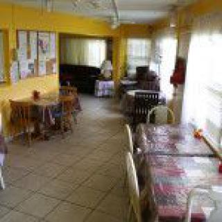 A cozy dining area with yellow walls and multiple tables and chairs.