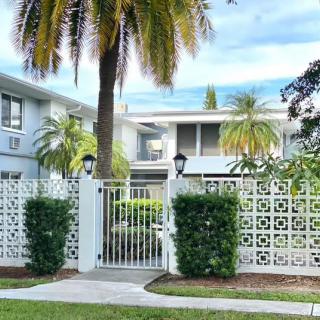 A modern white house with a decorative fence and palm trees in the yard.