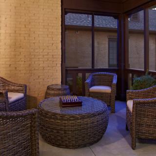 An outdoor patio with wicker furniture set including chairs and a round table.