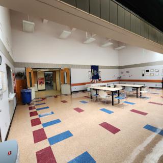 A spacious classroom setting with tables arranged and colorful flooring.