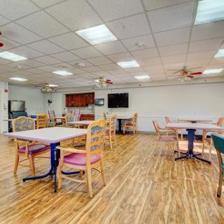 A spacious and well-lit dining area featuring several tables and chairs, designed for social gatherings.