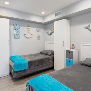 A neatly arranged bedroom with a nautical theme, featuring twin beds adorned with blue accents.