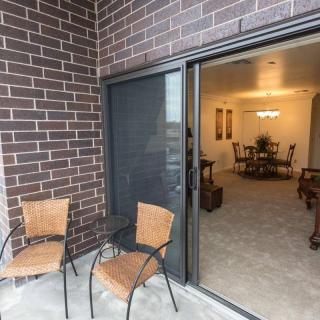 A cozy balcony with two chairs overlooking an interior dining area through a sliding glass door.