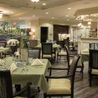 A cozy restaurant dining area with elegantly set tables and comfortable chairs, featuring warm lighting and tasteful decor.