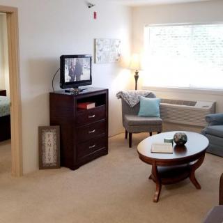 A cozy living room with comfortable seating, a television, and a window letting in natural light.