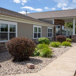 A well-maintained residential building with landscaped gardens under a partly cloudy sky.