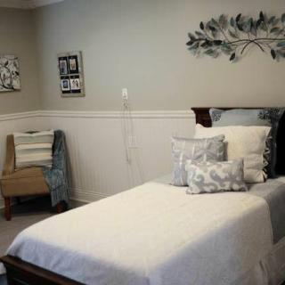 A cozy bedroom with a single bed, decorative pillows, and wall art in neutral tones.