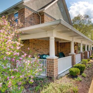 A brick house with a spacious porch and well-maintained garden.