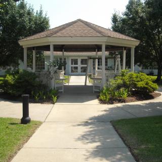 A peaceful gazebo surrounded by a landscaped garden and trees.