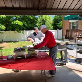 Two friends preparing food on a sunny day in the backyard.