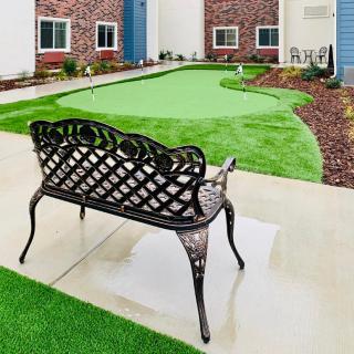 A neatly landscaped garden with a wrought iron bench and artificial grass.