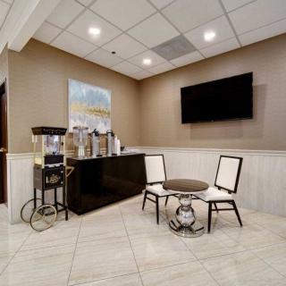 A modern waiting area with seating and a beverage station, featuring a coffee machine and water dispenser.