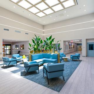 A bright and modern lobby with blue seating and lush plants, designed for comfort and relaxation.