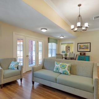 A cozy living room with a comfortable sofa, armchair, and elegant chandelier.