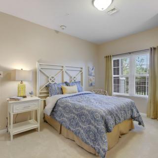 A cozy bedroom with a neatly made bed, nightstand, and a window with curtains.