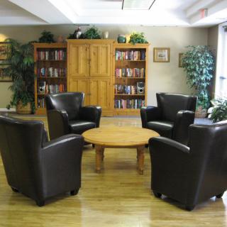 A cozy library corner with leather chairs and wooden bookshelves.