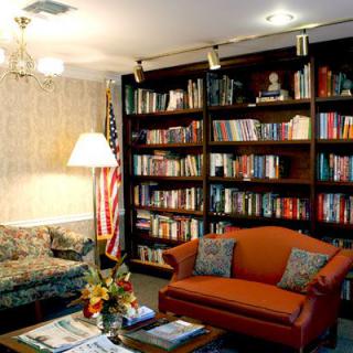 Cozy library room with bookshelves, sofas, and an American flag.