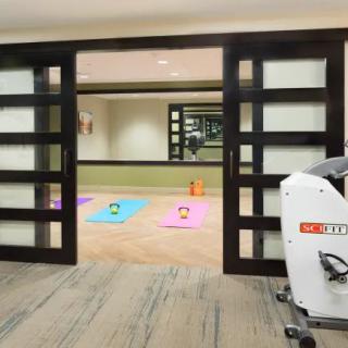 A fitness room with vibrant yoga mats ready for use, featuring wooden sliding doors and a mirrored wall.